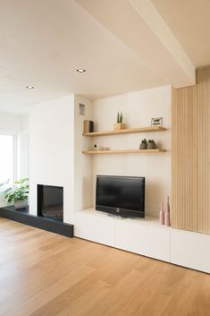 an empty living room with wood flooring and white wall mounted entertainment center in the corner