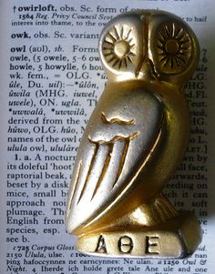 an owl figurine sitting on top of an open book with the word aoe written below it