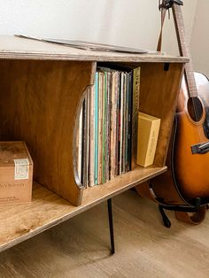 a guitar and some books on a shelf next to a book case with a box