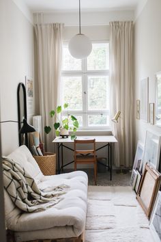 a living room filled with furniture next to a window covered in blankets and pictures on the wall