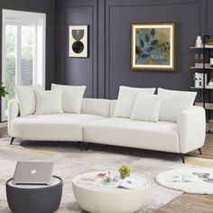 a living room filled with furniture and a laptop computer on top of a white couch