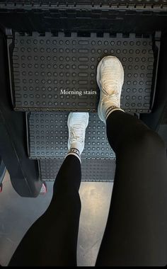 the feet of a person standing in front of a metal shelf with writing on it