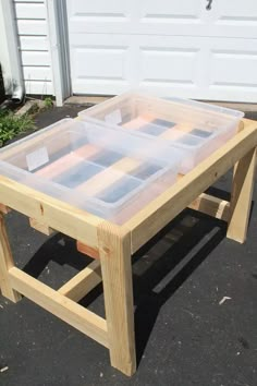 a wooden table with clear plastic containers on it's top and two legs in front of a garage door