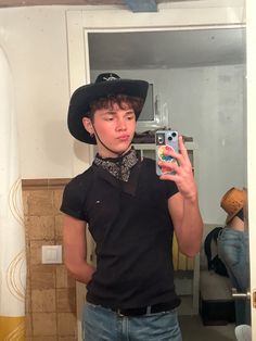 a young man wearing a cowboy hat taking a selfie