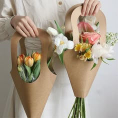 someone holding two bouquets with flowers in them, one is wrapped in brown paper