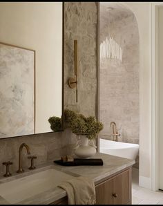 a white sink sitting under a large mirror next to a wall mounted faucet