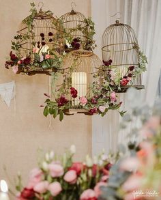 three bird cages with flowers and greenery hanging from the ceiling next to each other