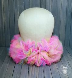 a white mannequin head with pink and yellow tulle