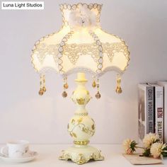 a lamp that is on top of a table next to a cup and saucer