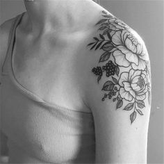 a black and white photo of a woman's shoulder with flowers on her left arm