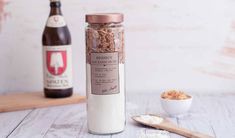 a bottle and spoon sitting on a table next to two bottles of wine, one with granola in it