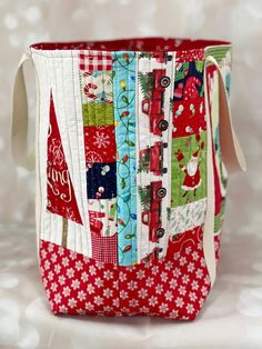 a red and white quilted bag with christmas decorations on it's side, sitting on a table