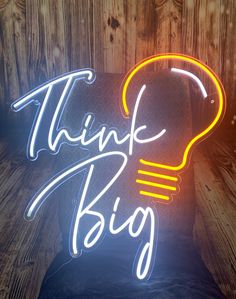 a neon sign that says think big with a lightbulb on the top of it