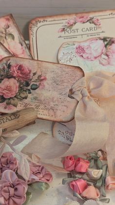 some pink flowers and old cards on a table