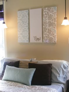 two paintings hang on the wall above a bed in a room with brown and white pillows