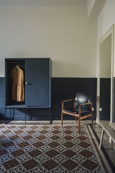 an empty chair sits in front of a blue cabinet with a coat hanging on it