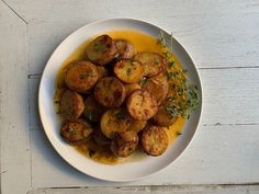 a white plate topped with potatoes covered in gravy and garnished with herbs