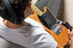 a man wearing headphones and holding an electric guitar