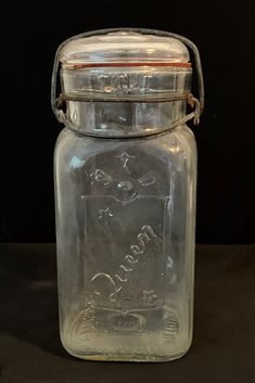 a glass jar with a metal lid on a black tableclothed surface, containing the word love written in cursive writing