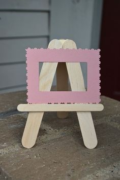 a small wooden easel with a pink frame