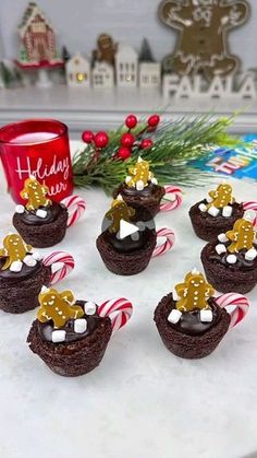 chocolate cupcakes decorated with christmas decorations and candy canes on a white table