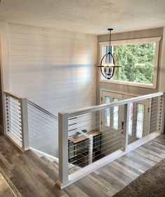 the inside of a house with white walls and wood flooring, stairs leading up to a second story window