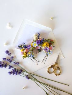 flowers and scissors on top of an envelope with pearls scattered around the envelope, which has been placed next to it