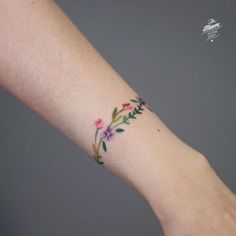 a woman's arm with a flower tattoo on the left side of her wrist