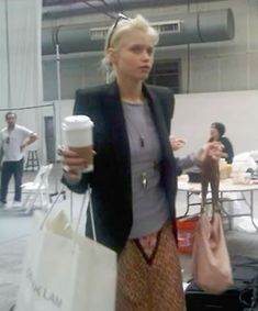 a woman holding a coffee cup in her right hand while standing next to another person