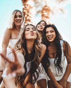 four women are laughing and posing for the camera with their hands in the air,