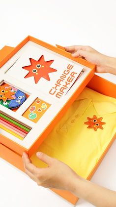 a child's hands holding an orange and white box