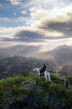 a man riding on the back of a white horse down a lush green hillside under a cloudy sky