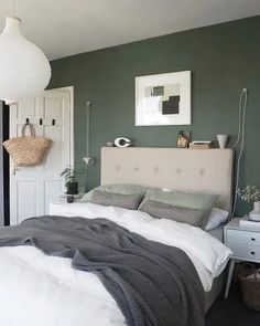 a bedroom with green walls and white furniture