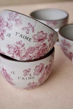 three pink and white bowls sitting on top of a table next to each other, with the words je t'aime printed on them