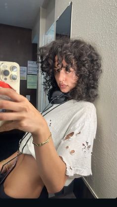 a woman taking a selfie in front of a mirror with her hair blowing back