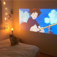 a cat sitting on top of a bed in front of a screen with anime characters