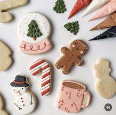 decorated cookies are arranged on a white surface with candy canes, snowman, and other decorations