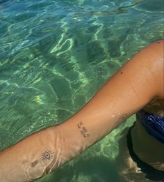 a person with a sun tattoo on their arm swimming in the clear blue ocean water