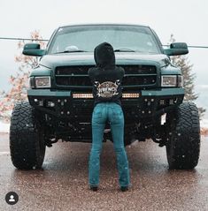 a person standing in front of a truck with its hood up and his hands on the bumper