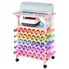 a pink cart filled with lots of different colored crayons and a machine on top