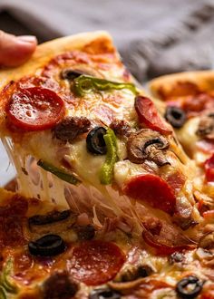 a slice of pepperoni pizza being held up by someone's hand with other slices