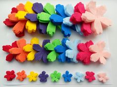 several different colored felt flowers on a white surface