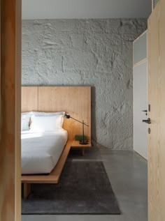 a bed sitting next to a wooden door in a bedroom on top of a rug