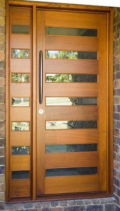 a modern wooden door with glass panels on the side and brick wall in front of it