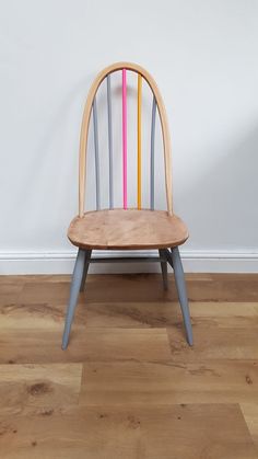 a wooden chair sitting on top of a hard wood floor next to a white wall