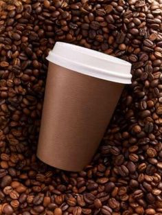 a coffee cup sitting on top of a pile of coffee beans