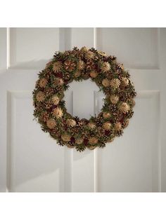 a wreath on the front door with pine cones and berries hanging from it's side