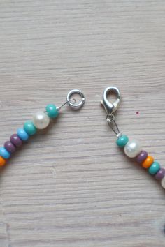 a close up of a beaded bracelet on a wooden table with a metal hook