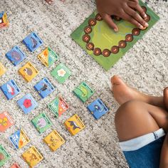 two children are sitting on the floor and playing with their matching board game pieces in front of them