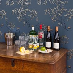 several bottles and glasses on a table with lemons, limes, and wine